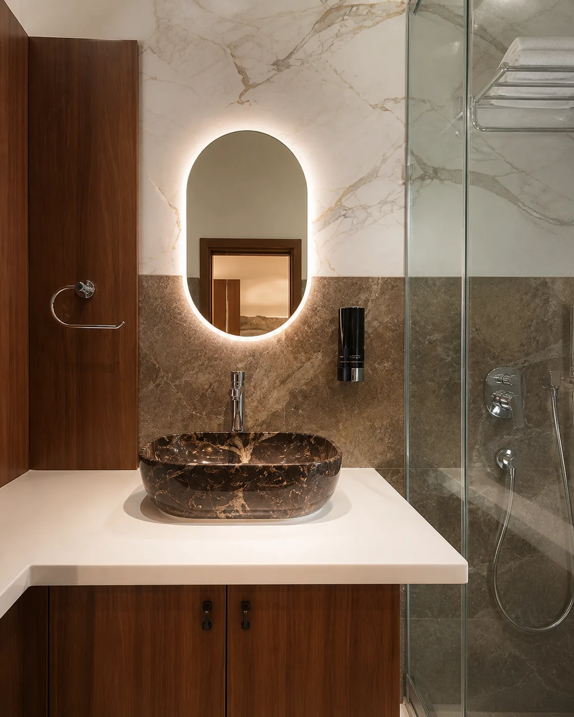 Karthikeya Grand bathroom with marble wall, timber vanity, and glass shower